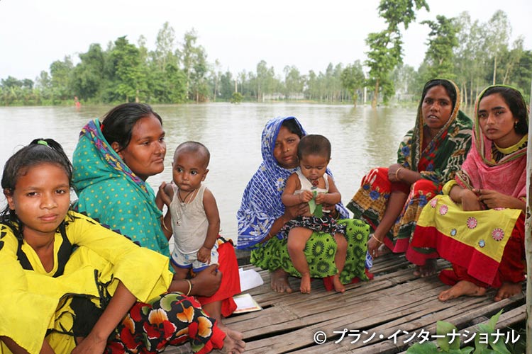 写真：バナナの茎で作ったいかだで洪水から避難する女性と子どもたち（バングラデシュ）