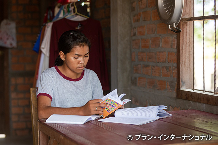 写真：自宅に机がないため隣人の家で勉強する女の子
