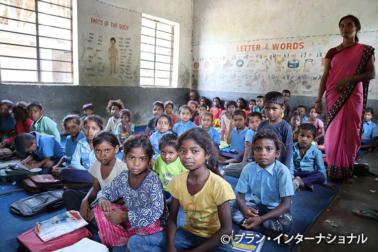 写真:机も椅子もない教室で、密集して学ぶ子どもたち
