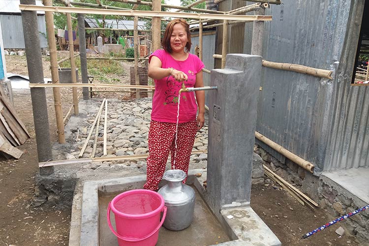 完成した家庭用水栓から水を汲む女性 / ©プラン・インターナショナル