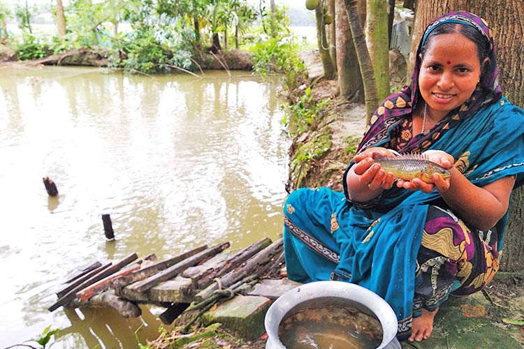 養殖をした魚が育ち、うれしそうな女性/ ©プラン・インターナショナル