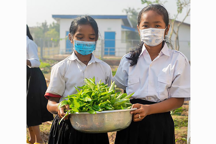 収穫した野菜を手に誇らしげな生徒たち / ©プラン・インターナショナル