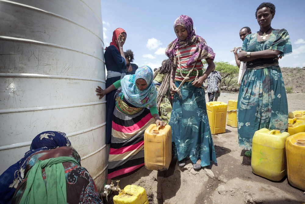 貯水タンクから、水を容器に汲む人々 / ©プラン・インターナショナル