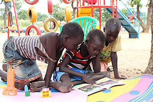 遊具だけでなく読書に熱中する子どもも（ウガンダ） / ©プラン・インターナショナル