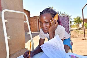 電話で家庭学習のサポートを受ける女の子（ジンバブエ） / ©プラン・インターナショナル