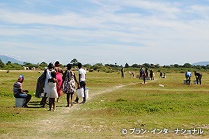 写真：支援物資を持って、歩いて村に帰る人々