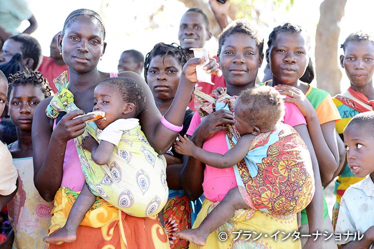 写真：支給された栄養食を子どもに食べさせる母親たち