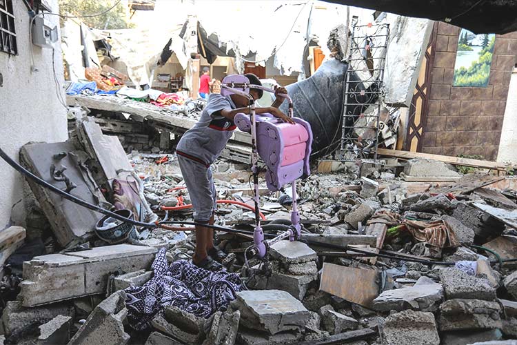 写真：被災した建物の瓦礫から所持品を引き揚げる男の子（copyright: Anas-Mohammed / Shutterstock.com）