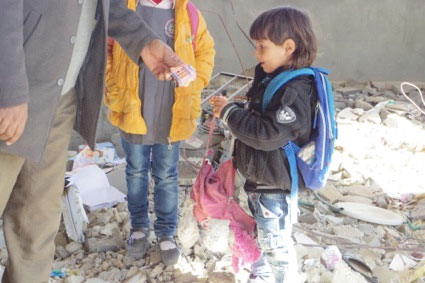 写真：がれきのなかからおもちゃや絵本を拾うイブラヒム