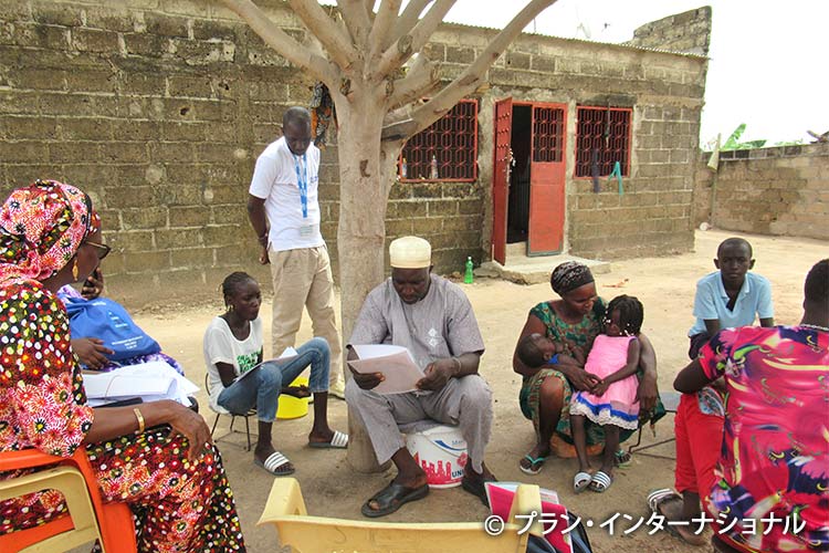 写真：家族のために手紙を代読するコミュニティ・ボランティア（中央）