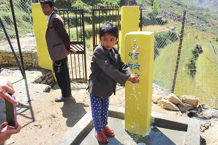 写真：完成した給水設備を利用する子ども