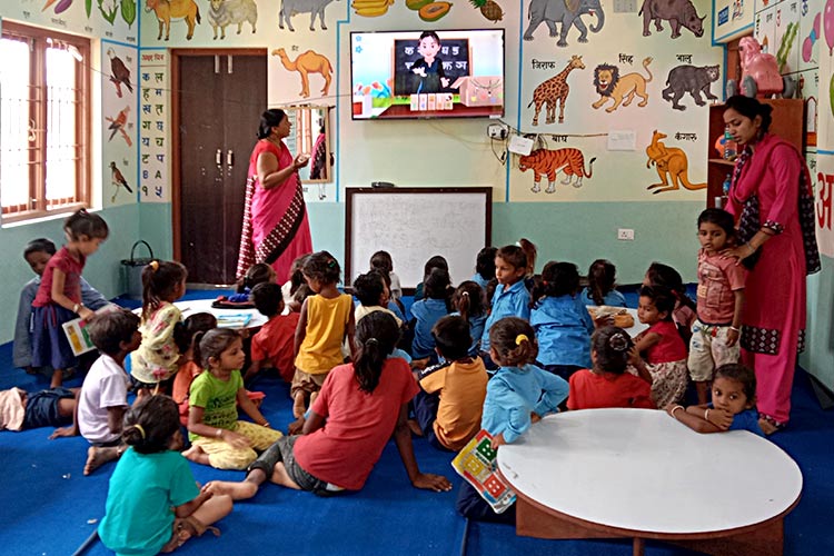 写真：モニターと円卓が設置された教室で学ぶ幼稚園の子ども