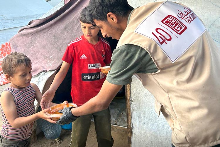 写真：ガザ地区国内避難民キャンプにて提供された温かい食事を受け取る子どもたち（パレスチナ）