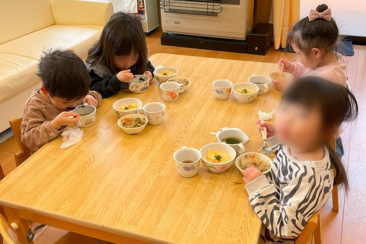 写真：再開したこども園で給食を楽しむ子どもたち
