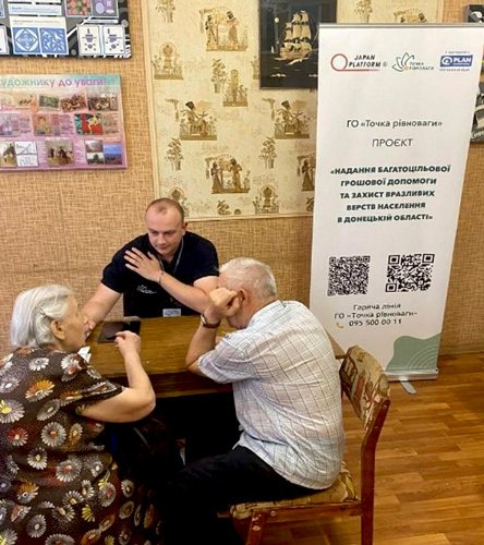 写真:現金給付を受ける人々の相談に乗る現地スタッフ(ウクライナ