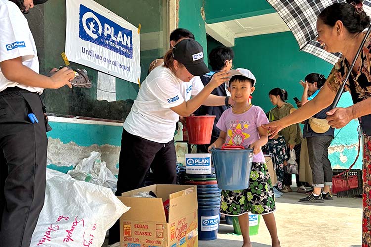 写真：家族と一緒に緊急支援物資を受け取る女の子