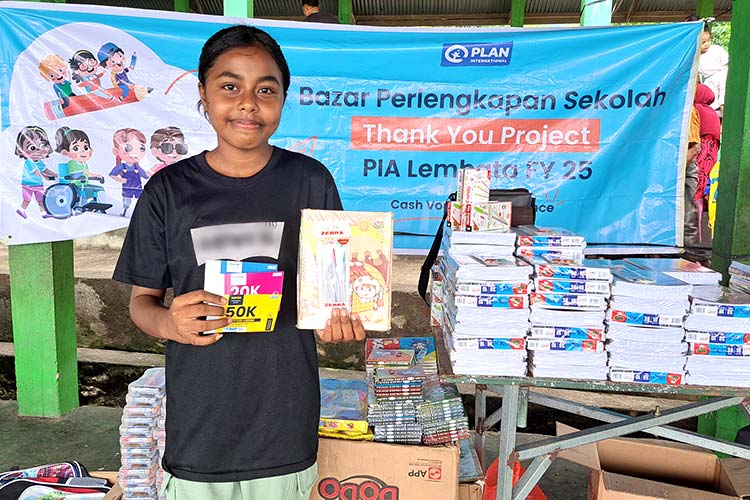 写真：学用品を受け取り笑顔を見せるルーさん