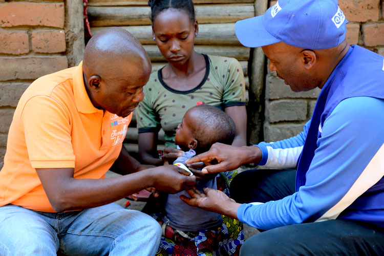 写真：栄養状態を見るために女の子の腕の太さを測るプラン職員（ジンバブエ）