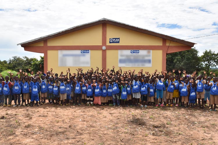 写真：完成した教室の前で笑顔を見せる子どもたち