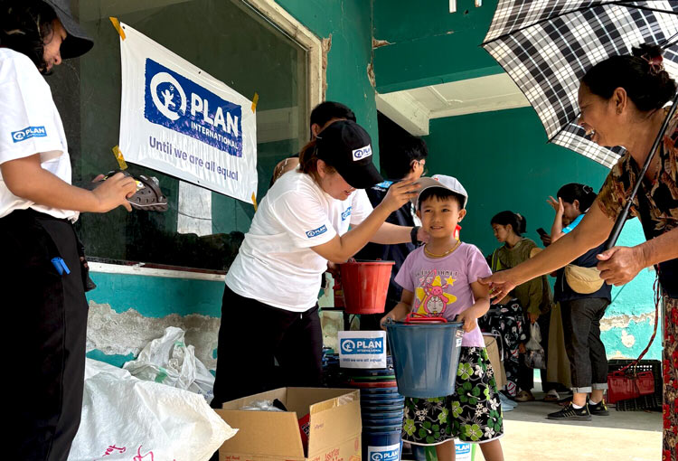 写真:家族と一緒に支援物資を受け取る女の子（ミャンマー）