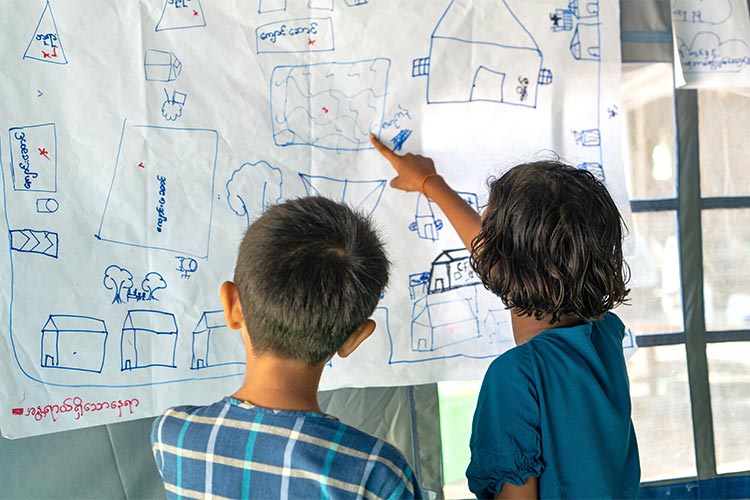 写真：「子どもひろば」で、自分たちで作った村のリスクマップを見ている子どもたち