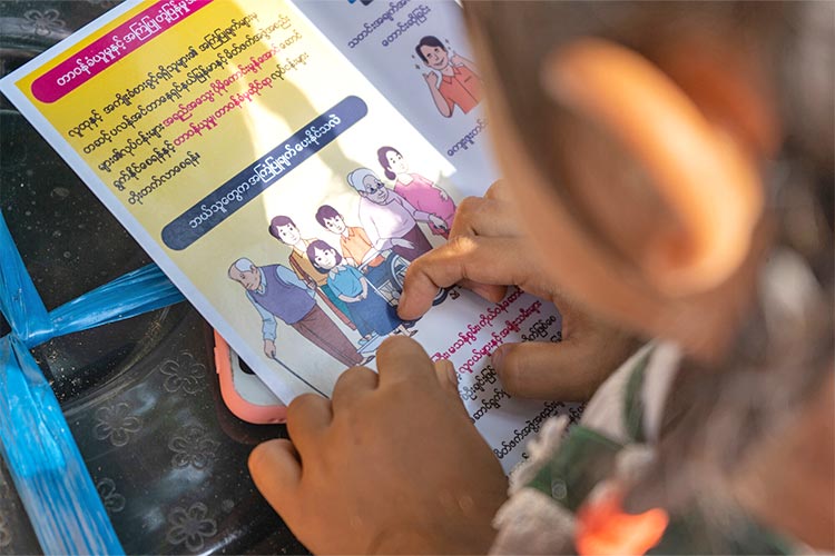 写真：緊急下の安全・保護に関するリーフレットを読む子ども