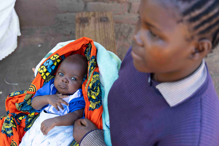 写真:妊娠のために中途退学した自分の子どもを抱く18歳の女の子(マラウイ)