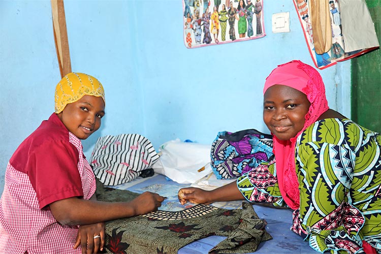 写真：指導員（右）から縫製を学ぶルマナさん