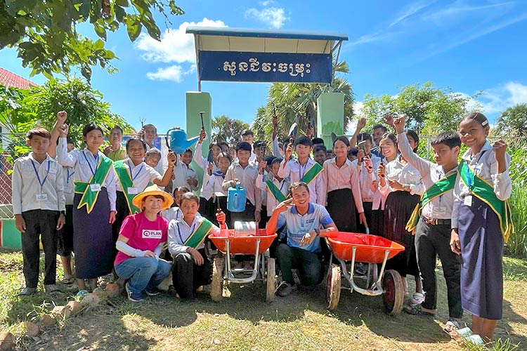 写真：笑顔はじける児童たちと、現地に出張した山形職員（前列左）