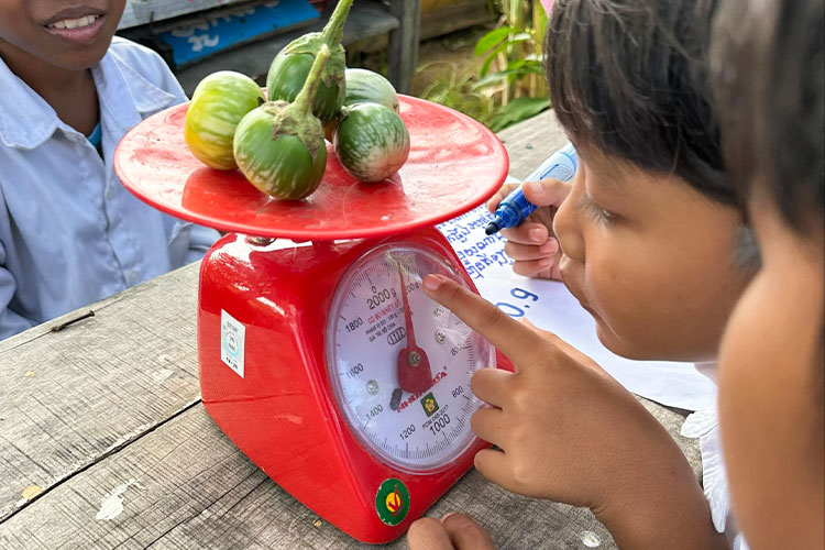 写真：収穫物の重さを計って記録する算数の授業