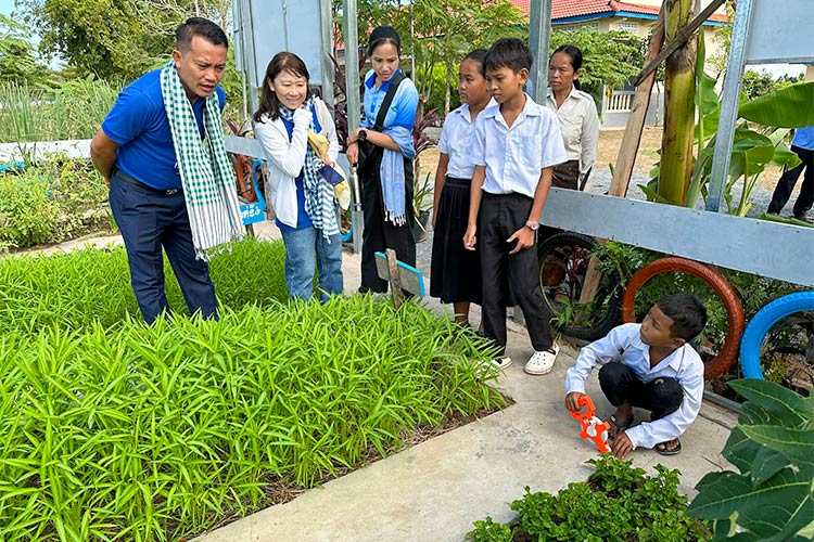 写真：学校菜園での活動を視察する山形職員（左から2人目）
