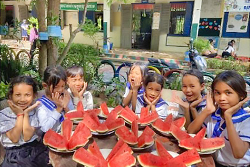 写真：スイカを囲む笑顔の子どもたち