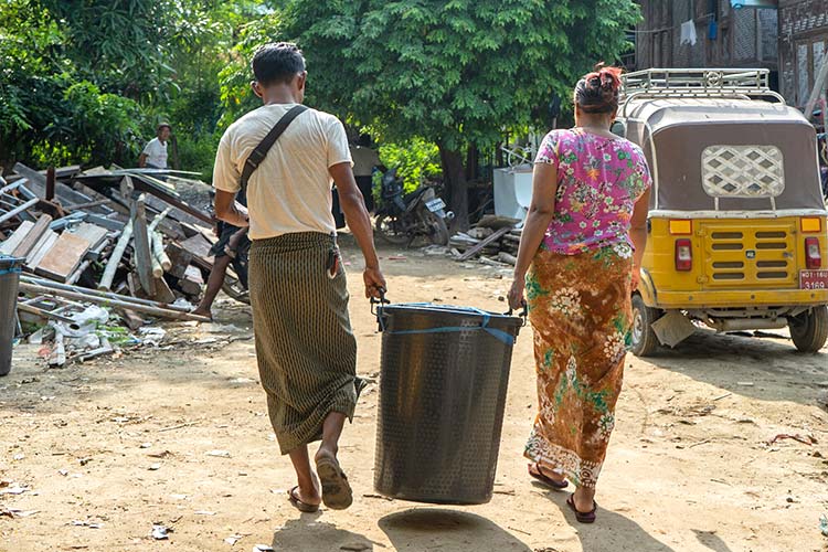 写真：タオルや下着を含む衣類、歯ブラシや石けんなどの「衛生キット」を受け取る家族