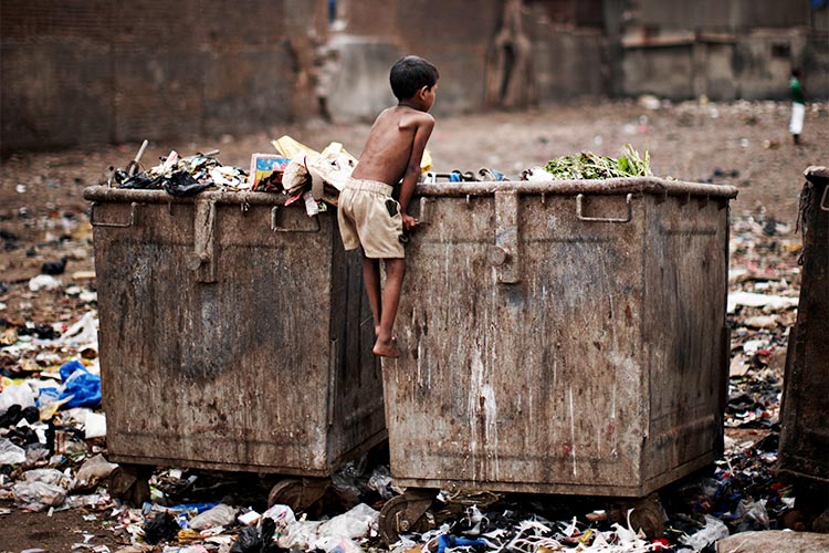 写真:スラム街でゴミの中を探す男の子(インド)