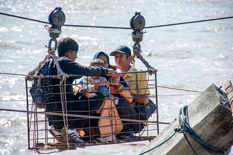 増水した川を滑車装置で渡る親子