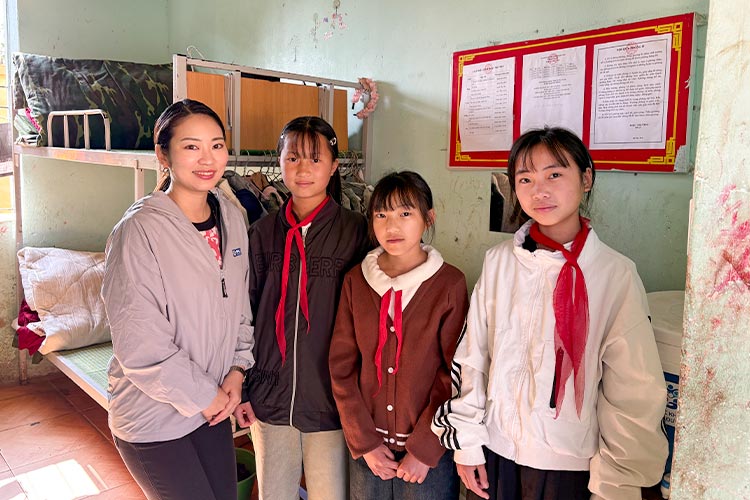 写真：対象校の寄宿舎で生活する女の子たちと駐在の水上職員（左）