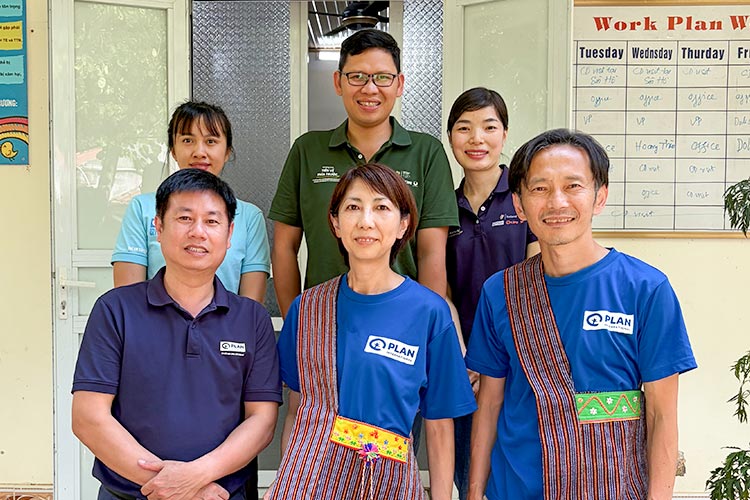写真：プラン・ベトナムの職員たちと。佐藤職員（下段中央）、番場職員（同右）