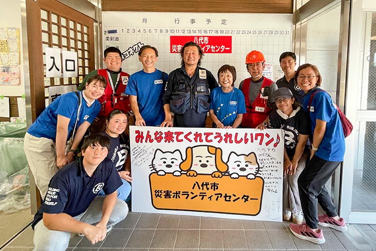写真：八代市災害ボランティアセンターにて。増田明美さんも活動に参加（左から5人目）