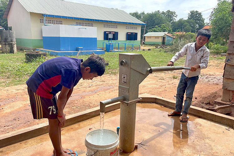 写真：給水施設が故障しているため、井戸の水を汲む児童