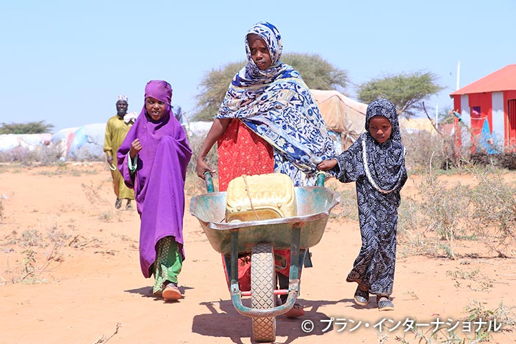 画像:幼いきょうだいを連れて水汲みに行く女の子