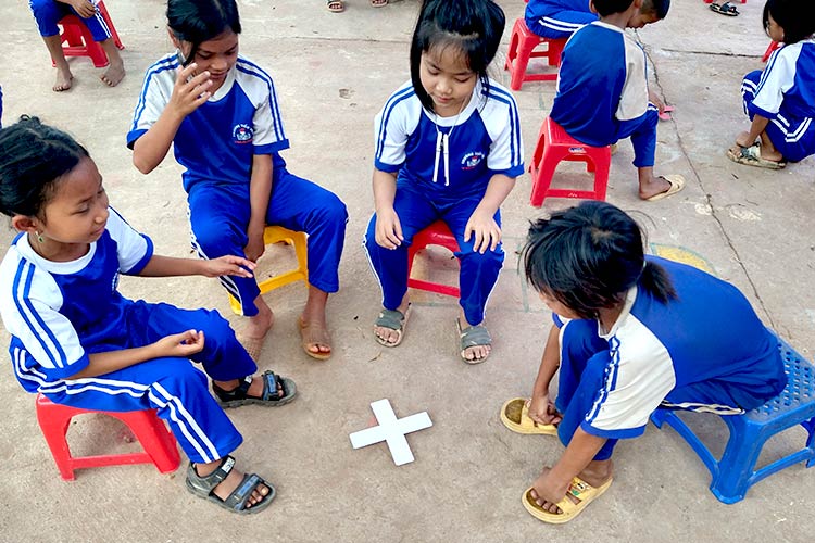 写真：お土産の手作りコマで遊ぶ子どもたち。縄跳びや文房具もプレゼントしました