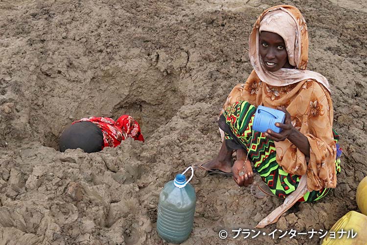 写真：干上がった川で水を汲もうとする女性（ケニア）