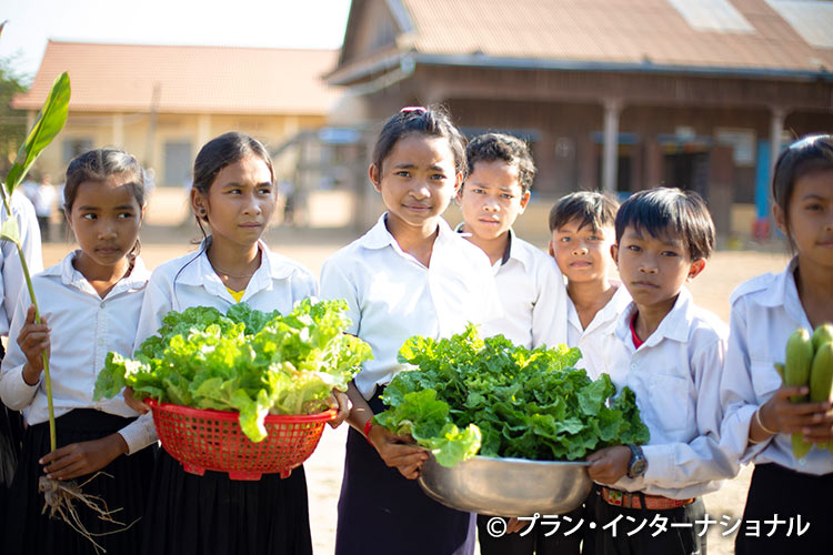 写真：収穫した野菜をもつ女の子と男の子