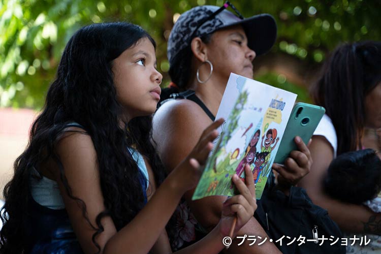 写真：プランが配布した子どもの保護に関する冊子を読む女の子