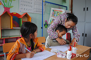 写真：教員アシスタント（右）は、少数民族の言語で授業を説明し、児童の理解を促進
