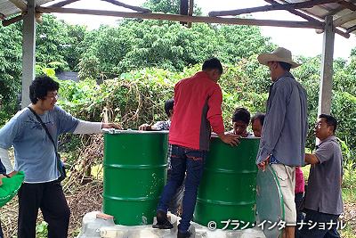 写真：ドラム缶を使ってキノコ栽培をする生産者グループメンバー