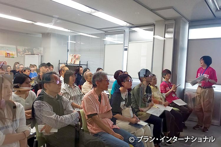 写真：報告をする篠原職員の話に熱心に耳を傾けている参加者たち