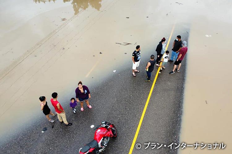 写真：冠水した道路で立ち往生する人々