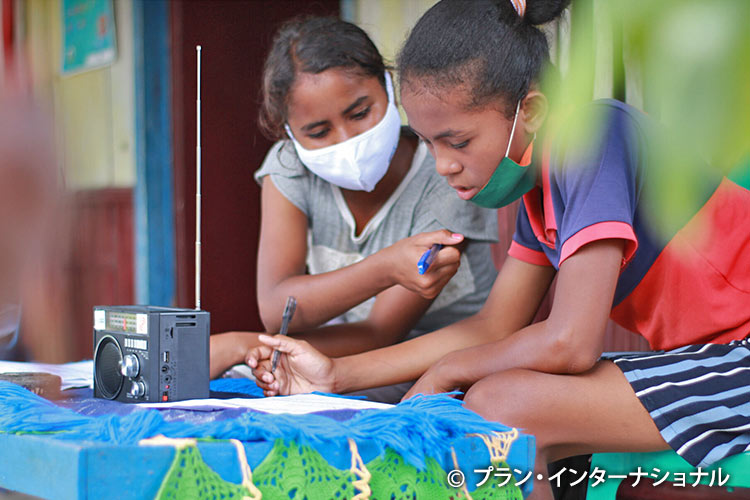 写真：プランが配布したラジオで勉強する女の子たち（インドネシア）