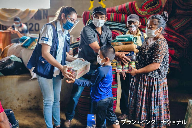 写真：避難所で緊急物資を受け取る家族